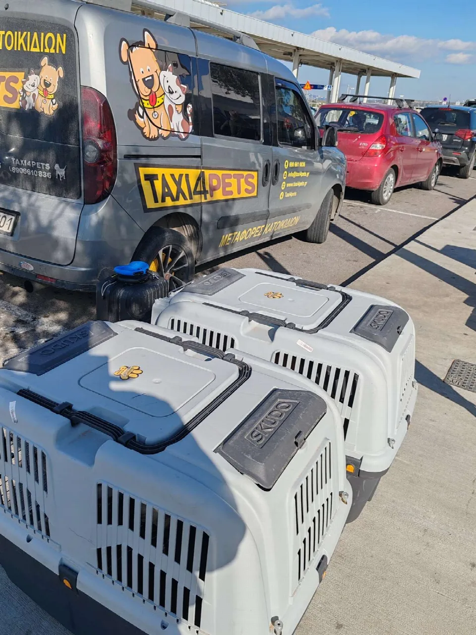 Κλουβιά μεταφοράς κατοικιδίων δίπλα στο όχημα του Taxi4Pets στο αεροδρόμιο